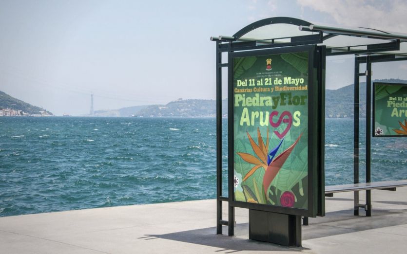Parada de guagua con cartel anunciador de la Feria Piedra y Flor de Arucas 2023
